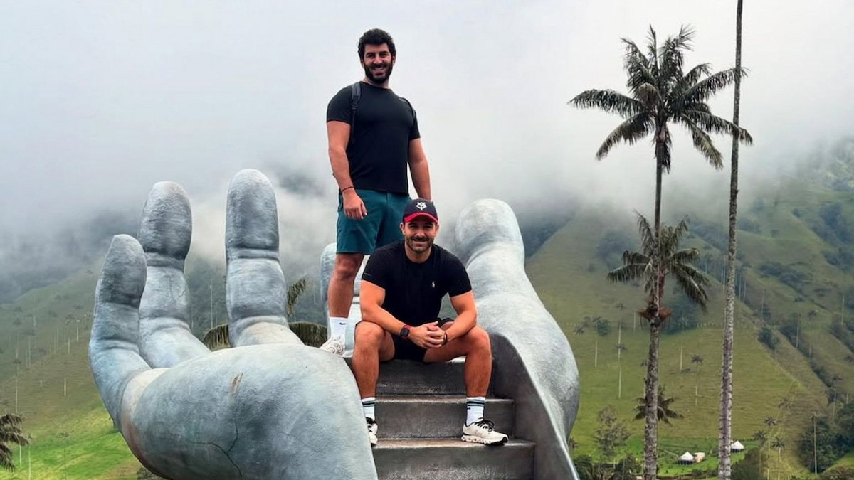 Travelers posing on a giant hand sculpture near Cocora Valley, Salento, Colombia
