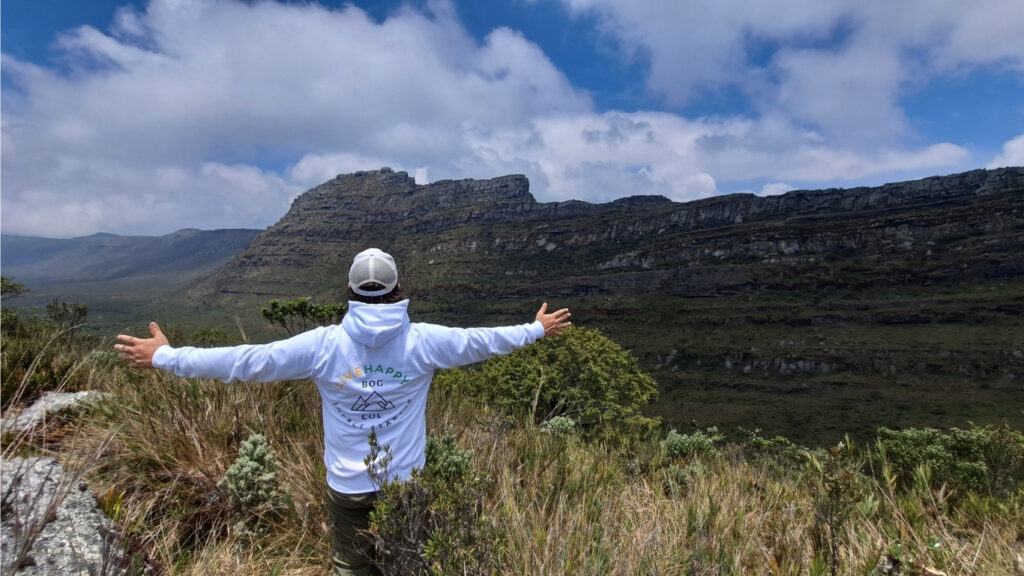 A hiker with arms outstretched on the páramo ridge in Chingaza