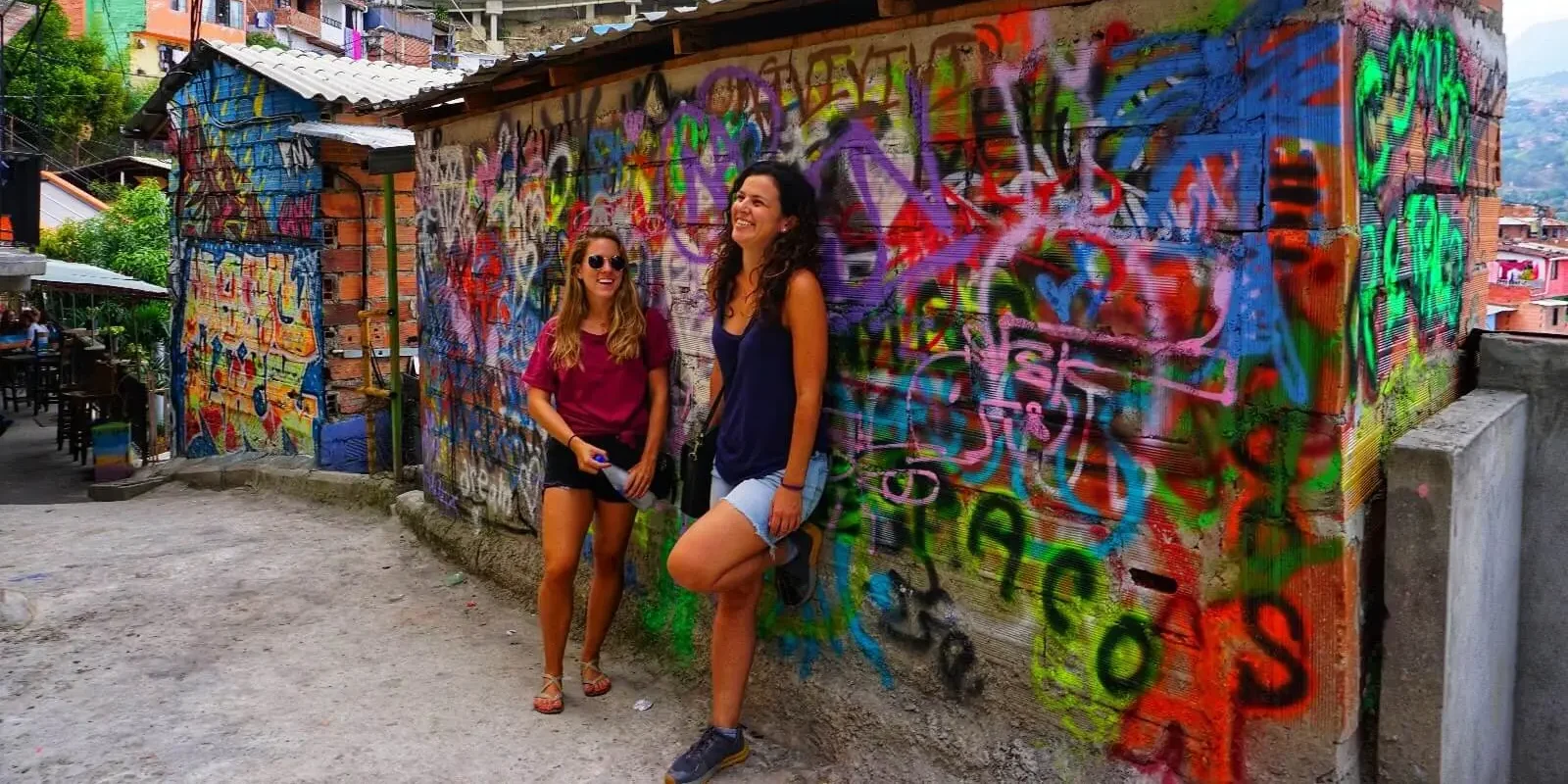 Travelers standing by a graffiti-covered house during a Graffiti Tour Medellin in Comuna 13, Medellin, Colombia