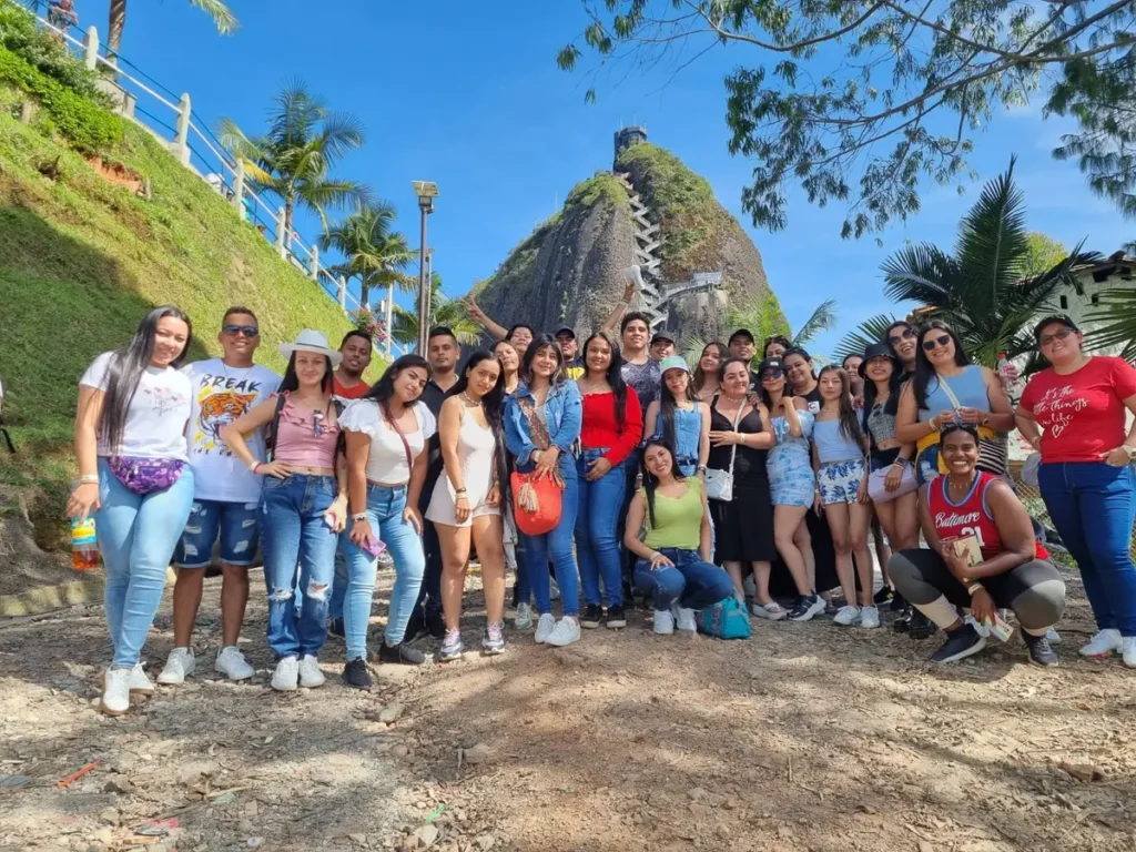 Travelers posing by the Guatapé sign and El Peñol on a Guatape Tour in Colombia