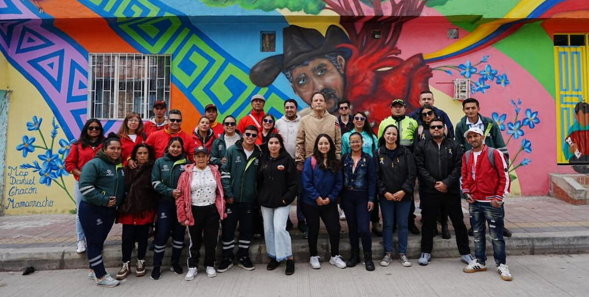 Community group posing in front of a mural in El Paraíso, Ciudad Bolívar, Bogotá, Colombia.