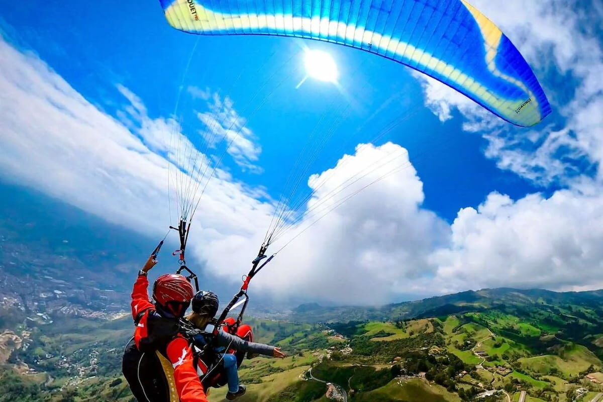 Tandem paragliding in Medellín above green mountains and clouds, Colombia