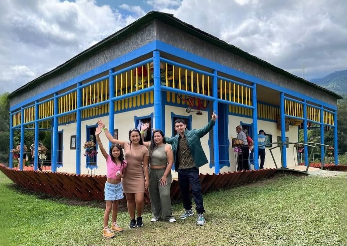 Family posing in front of a colorful farmhouse at a coffee farm in Quindío, Colombia