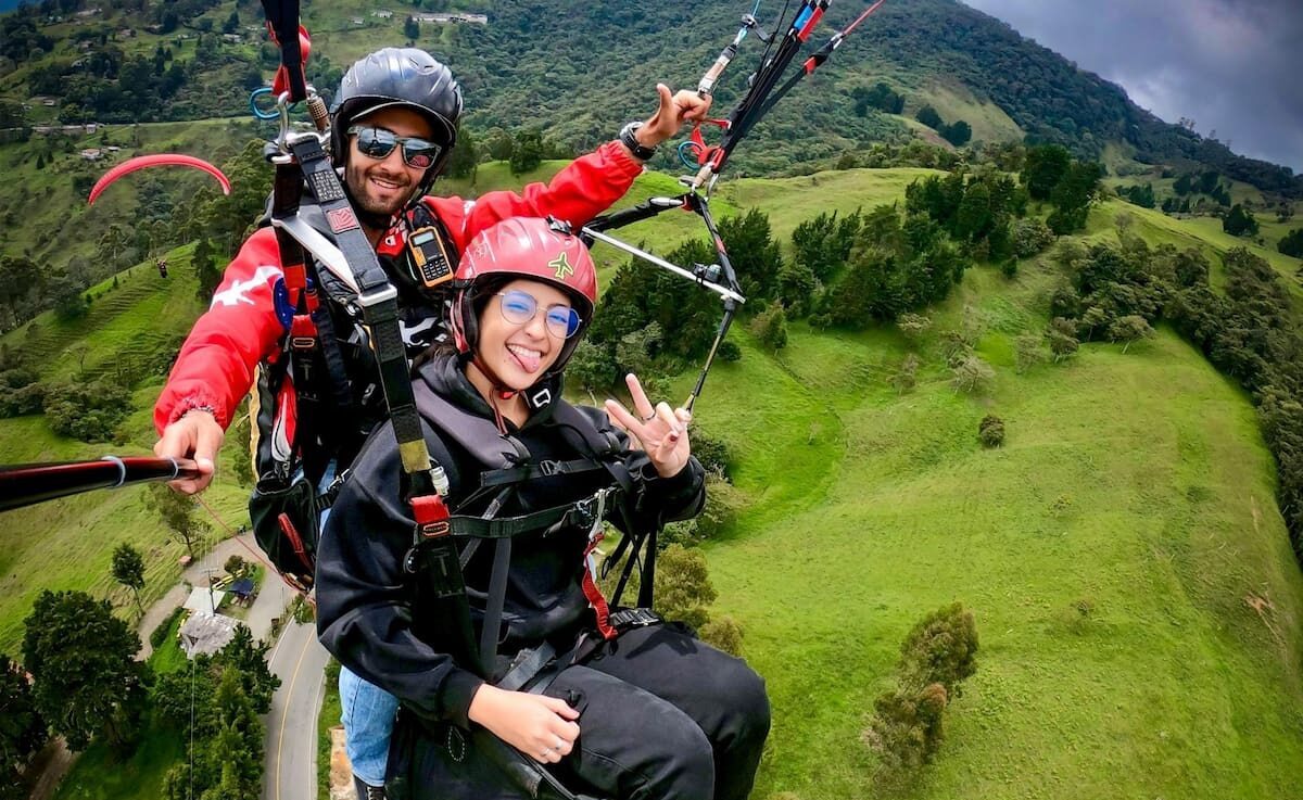 Smiling travelers paragliding in Medellín over the hills near Medellín, Colombia
