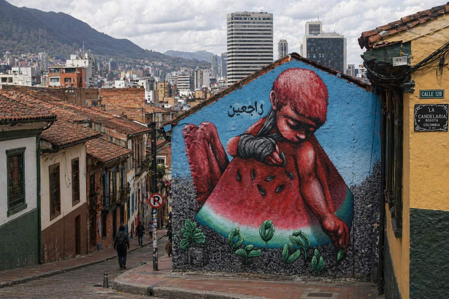 large mural of a red-toned human figure painted on a building wall with Bogotá skyline and mountains in the background Colombia
