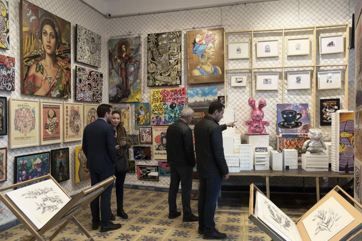 visitors observing contemporary artworks inside a gallery space filled with paintings and framed pieces in Bogotá Colombia