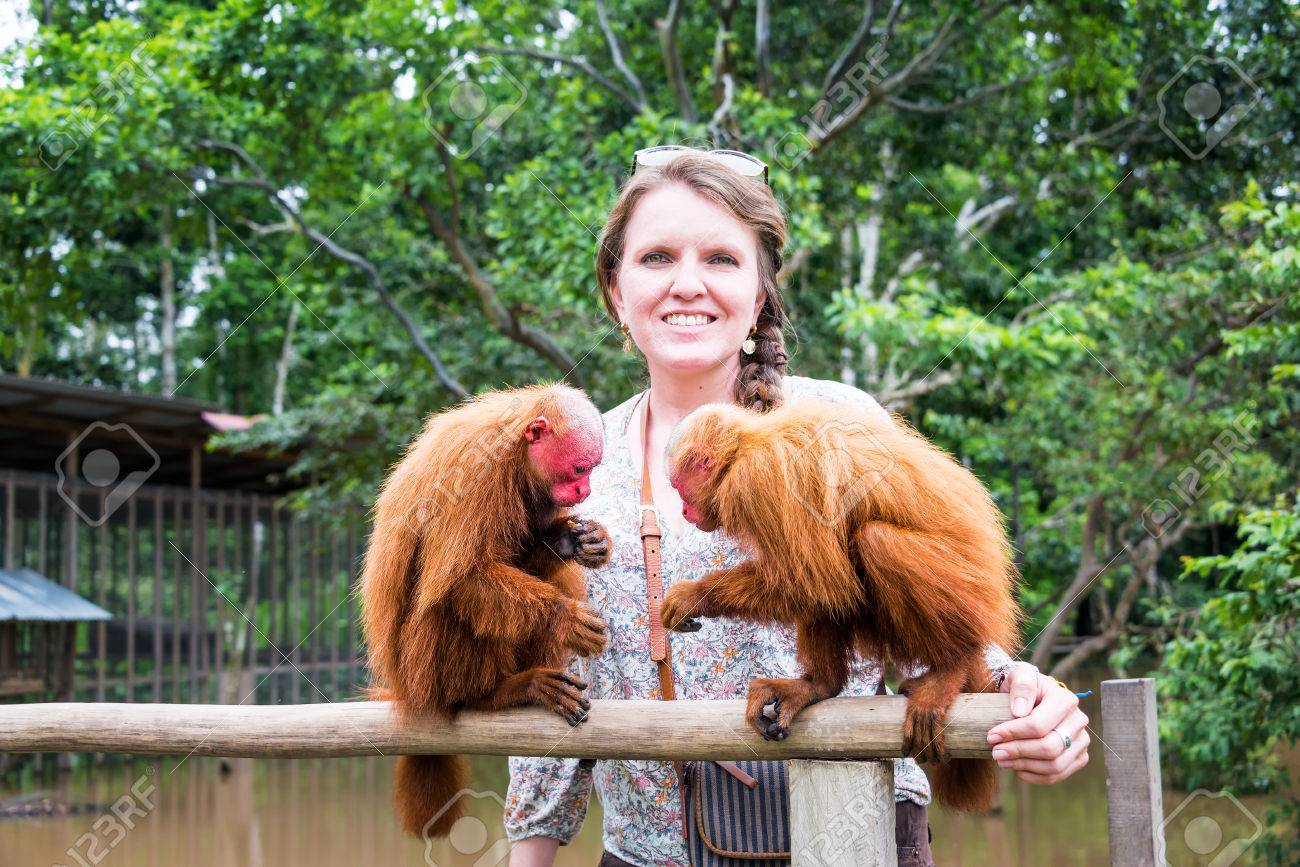 Traveler posing with two red uakari monkeys during a 5 day Amazon tour in the Colombian Amazon.