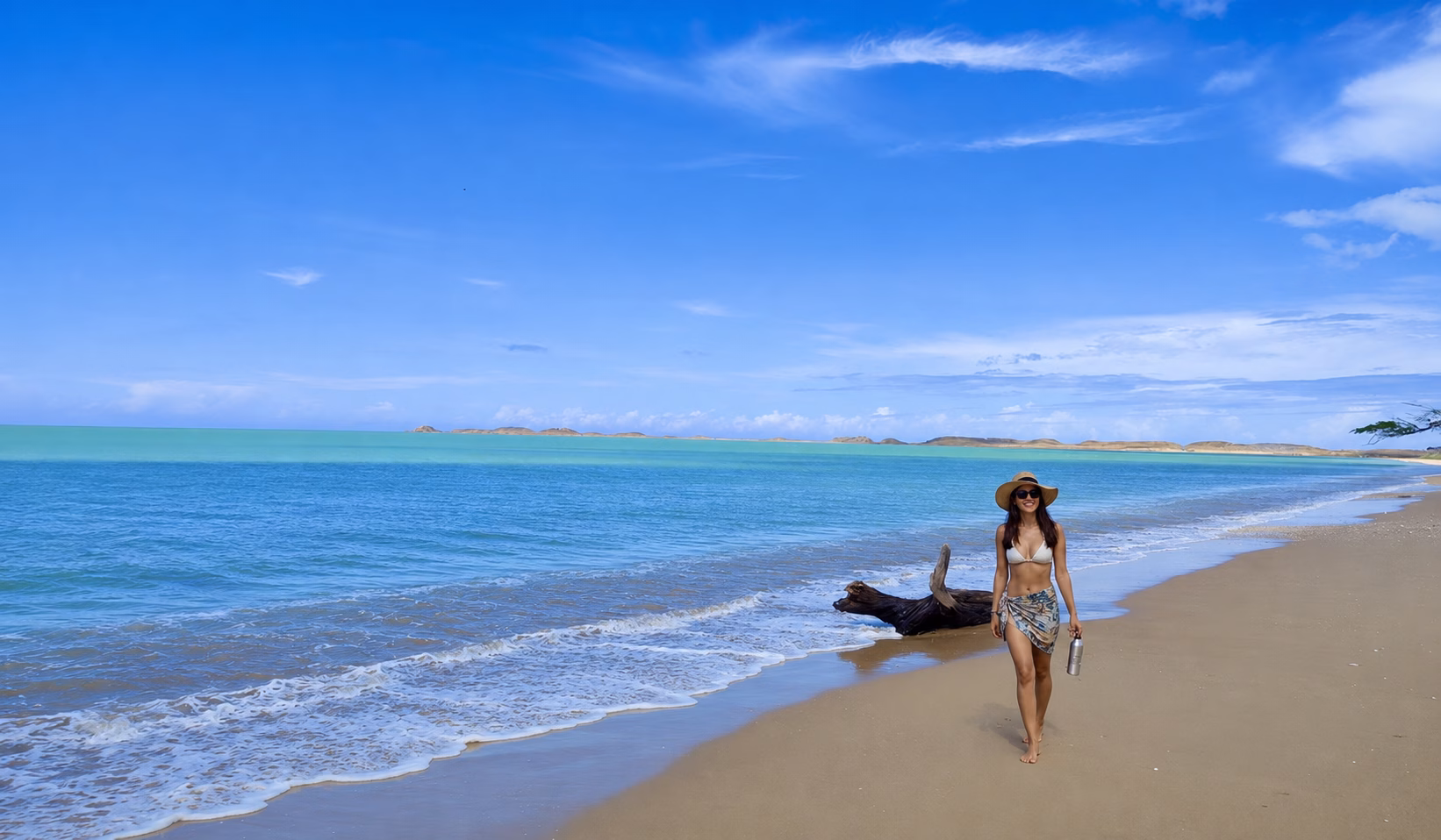 Woman walking along a quiet beach with turquoise water during the 3 day tour La Guajira.