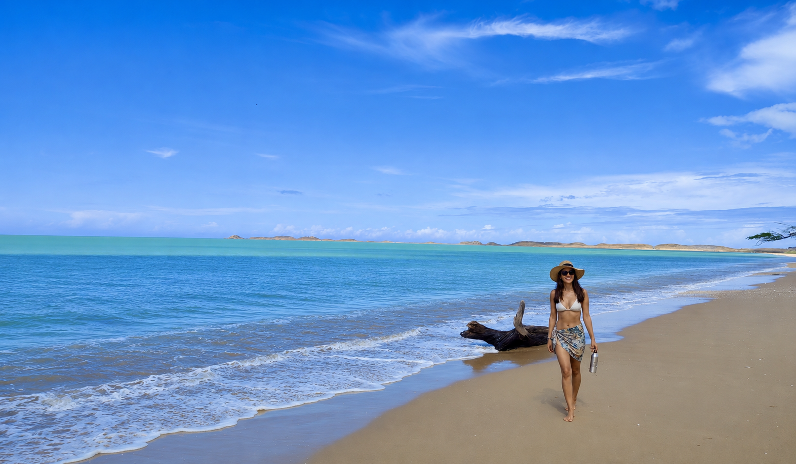 Woman walking along a quiet beach with turquoise water during the 3 day tour La Guajira.