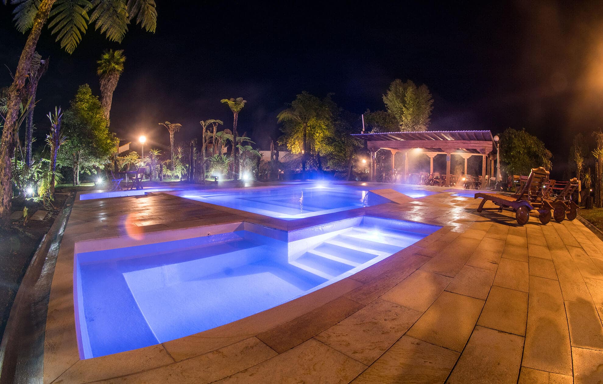 Illuminated outdoor thermal pools at night during an Otoño Hot Springs Trip in a peaceful mountain setting.