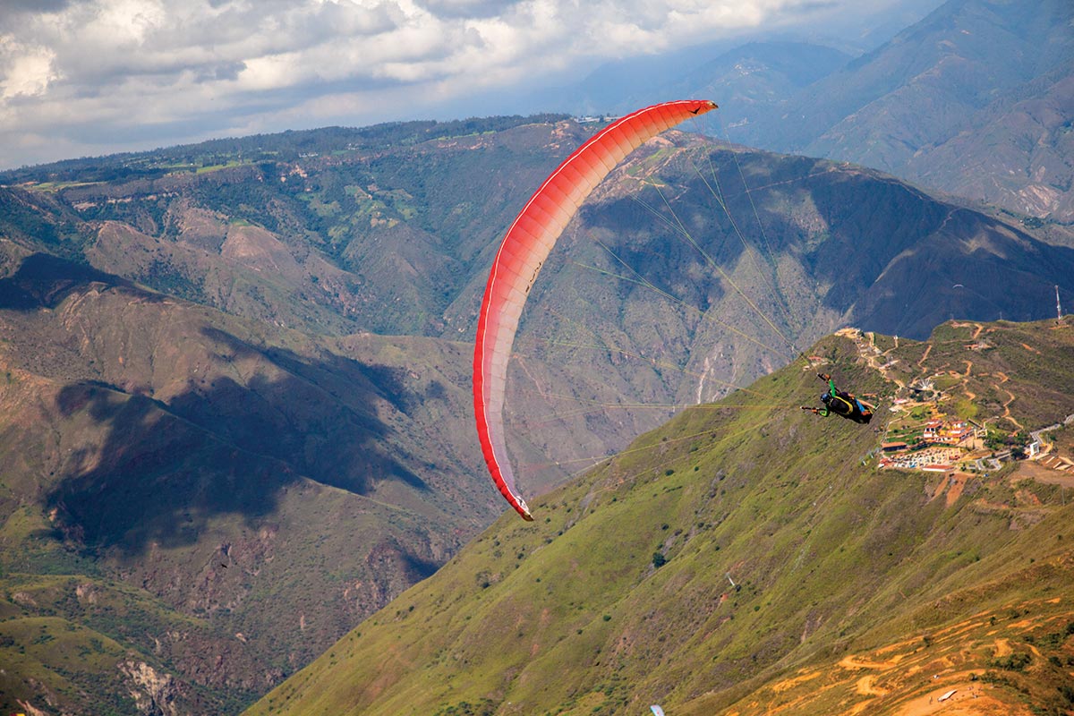 Paraglider flying over the dramatic mountain scenery and steep slopes of paragliding Chicamocha Canyon.