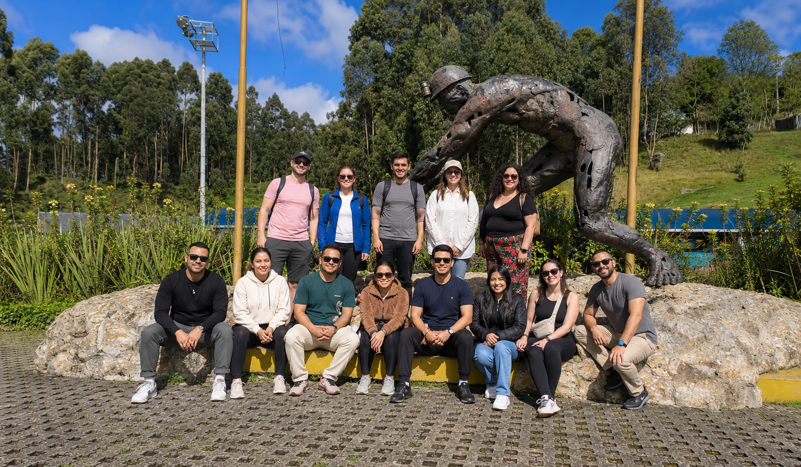 Travelers posing beside a miner sculpture surrounded by greenery during a 2 day tour Zipaquira Villa de Leyva in Colombia.