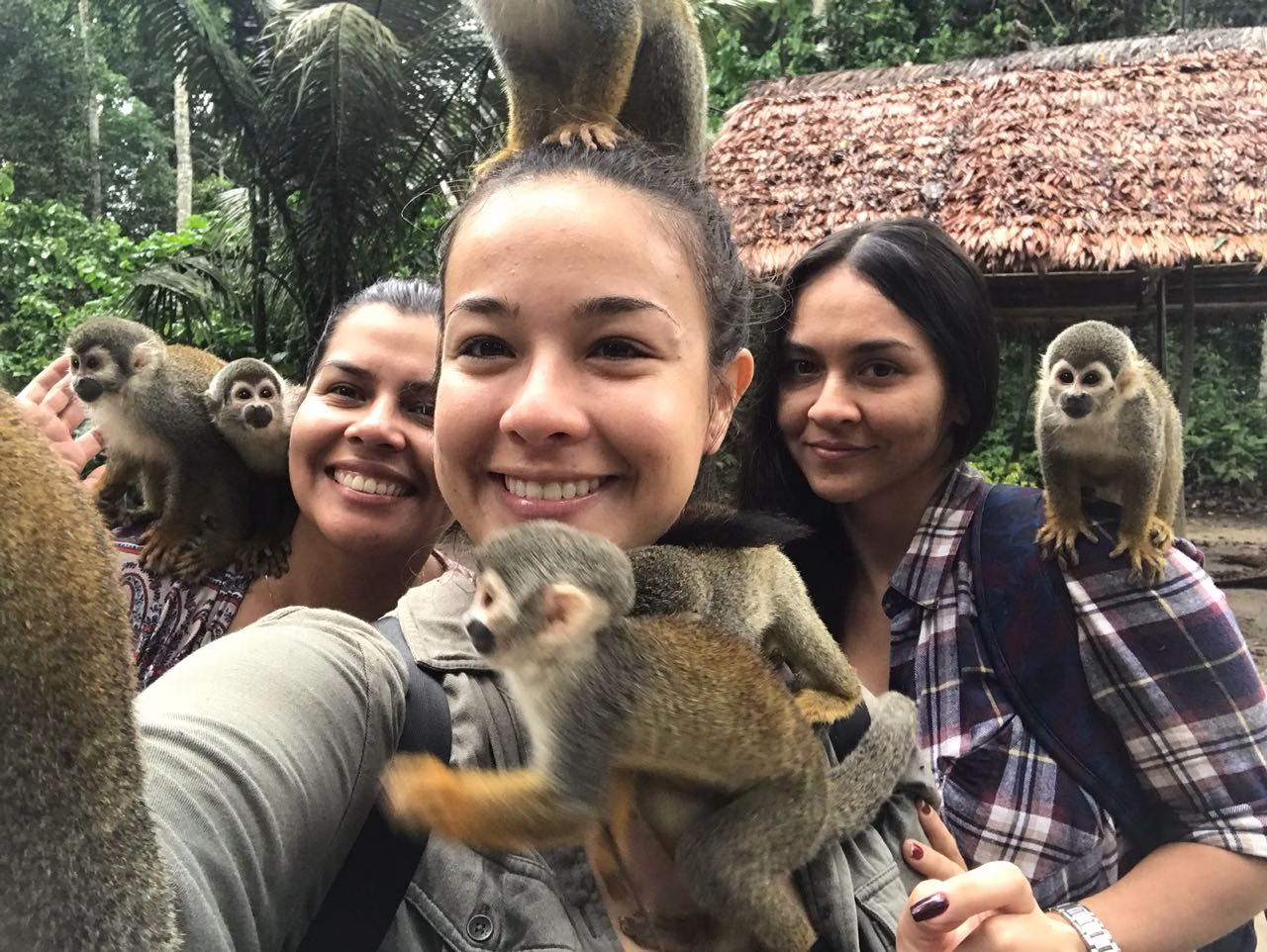 Group selfie with playful squirrel monkeys during an Amazon Three Borders Tour Colombia adventure.