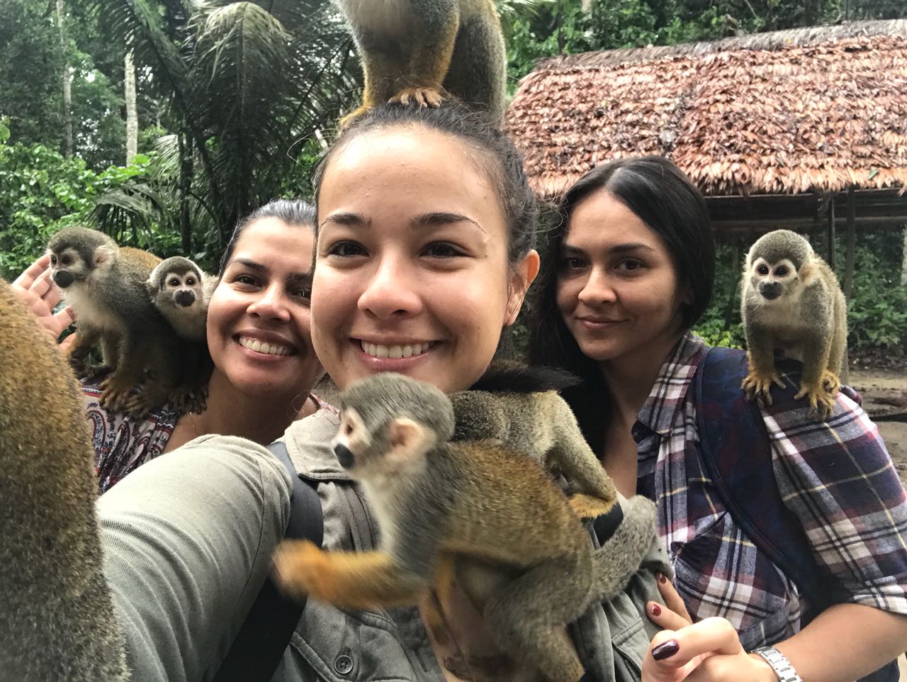 Group selfie with playful squirrel monkeys during an Amazon Three Borders Tour Colombia adventure.