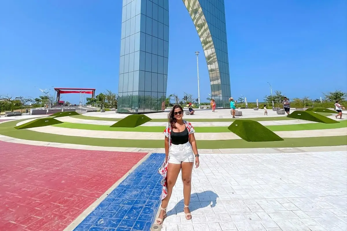 Woman posing beneath the iconic Ventana al Mundo monument during a Barranquilla City Tour.
