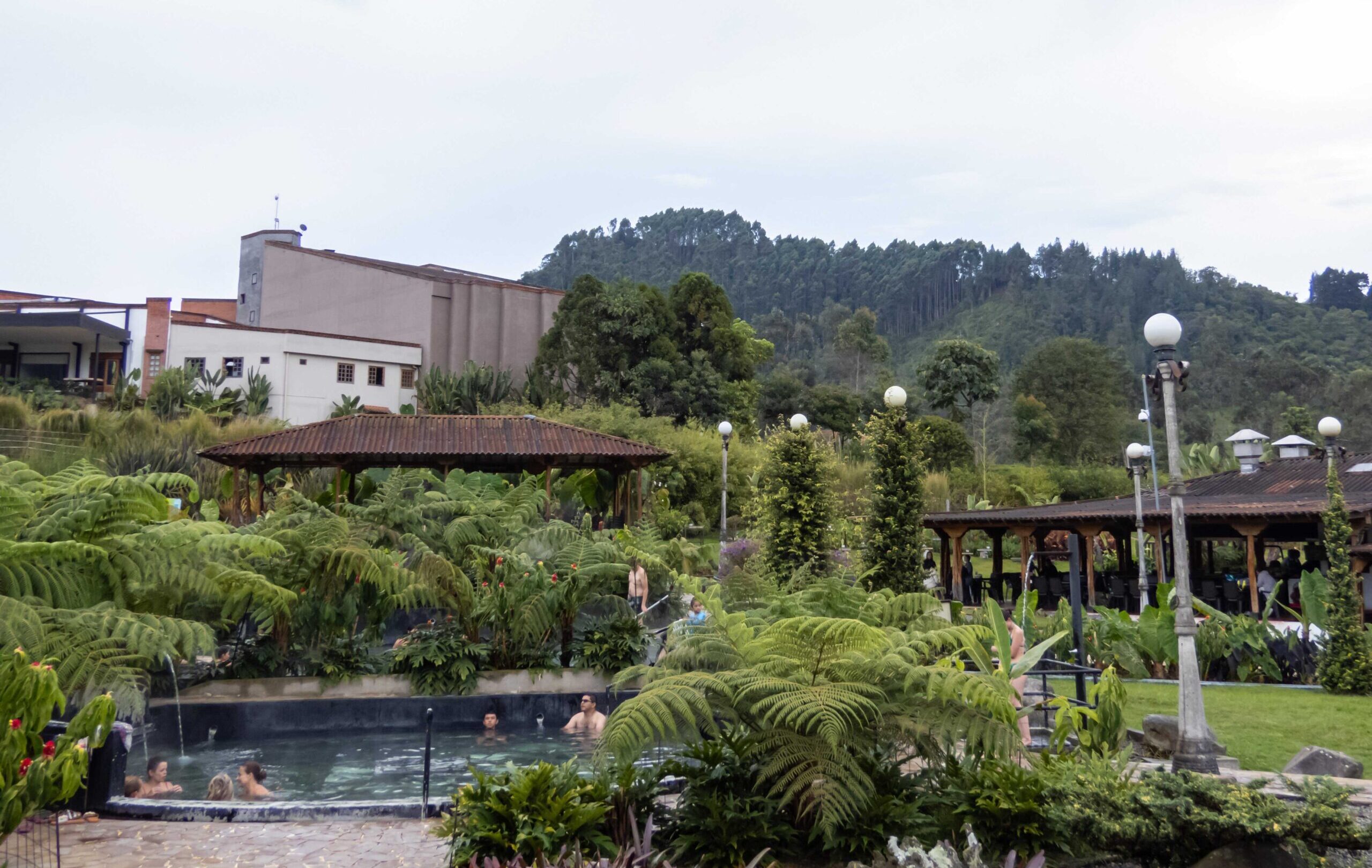 Lush garden and hot springs area with forested hills in the background on an Otoño Hot Springs Trip.