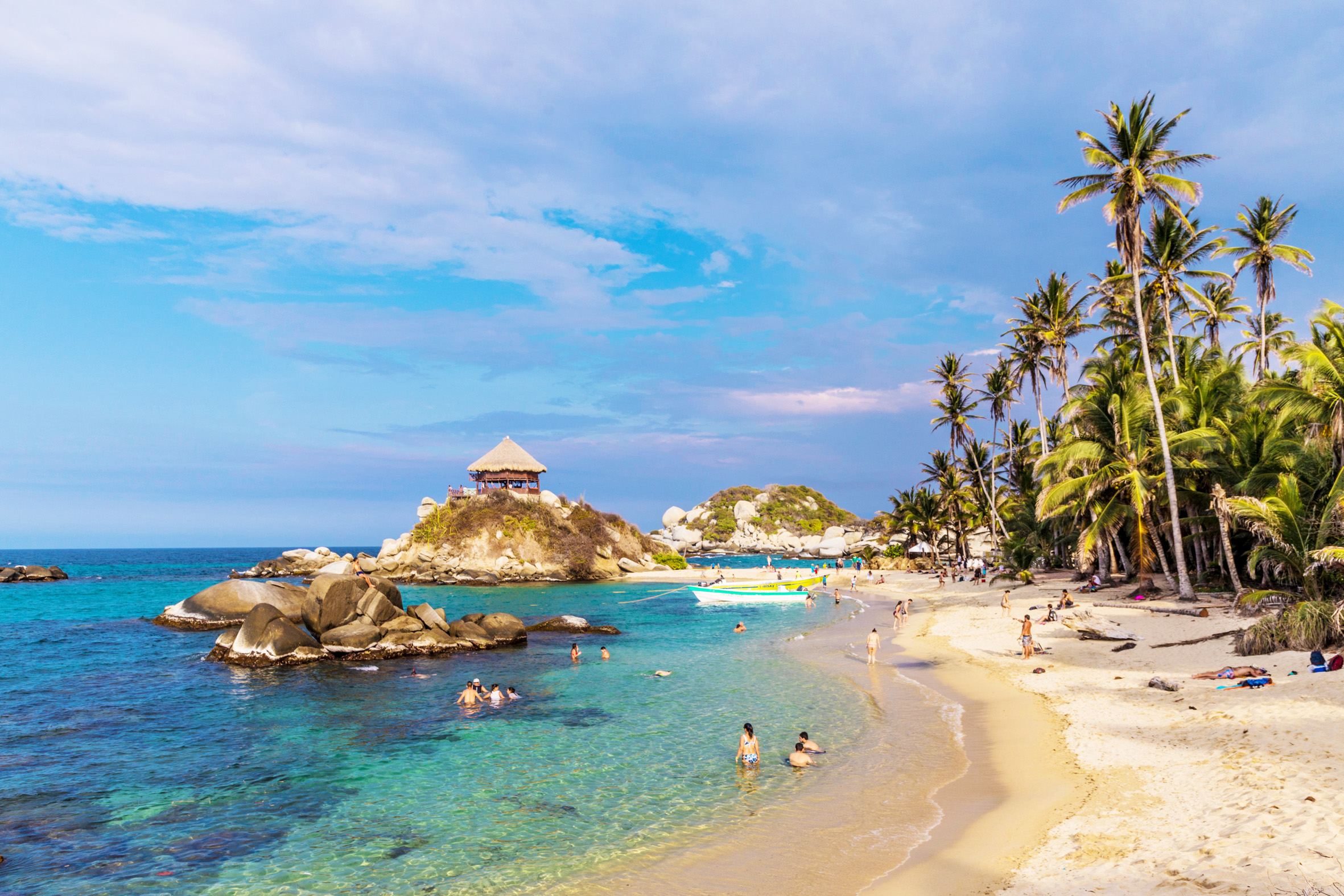 anoramic view of Cabo San Juan beach with crystal-clear water and palm trees during a Tayrona Park Tour.
