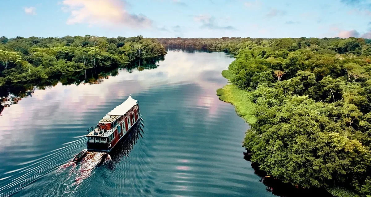 Boat sailing along a wide jungle river, a scenic highlight of an Amazon Three Borders Tour Colombia.
