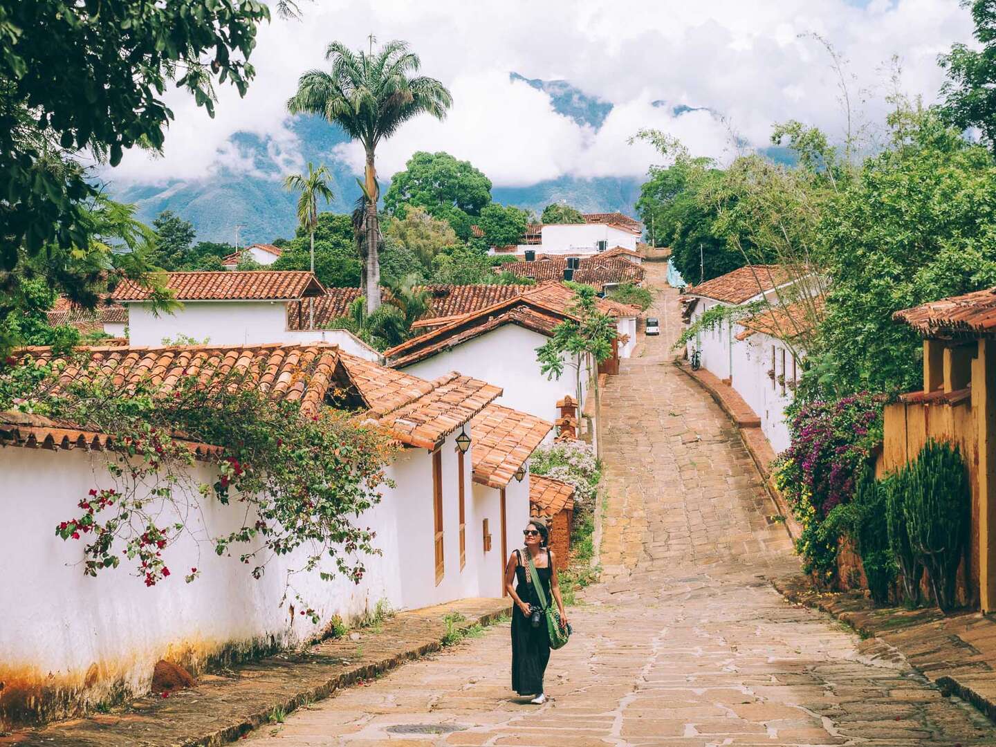 Woman walking along a peaceful colonial street with mountain views during a Barichara Tour.