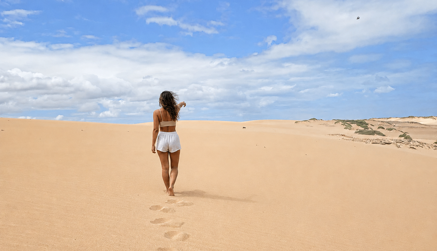 Woman walking barefoot across the dunes with footprints behind her on the 3 day tour La Guajira.