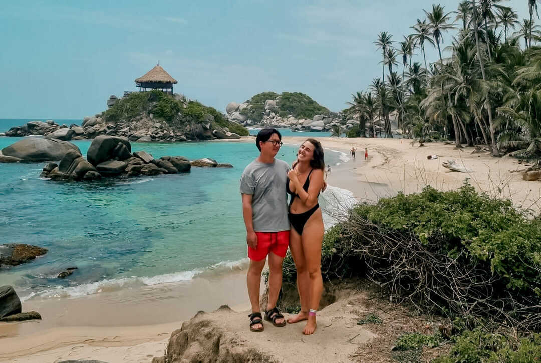 Couple posing on the beach with Cabo San Juan in the background during a Tayrona Park Tour.