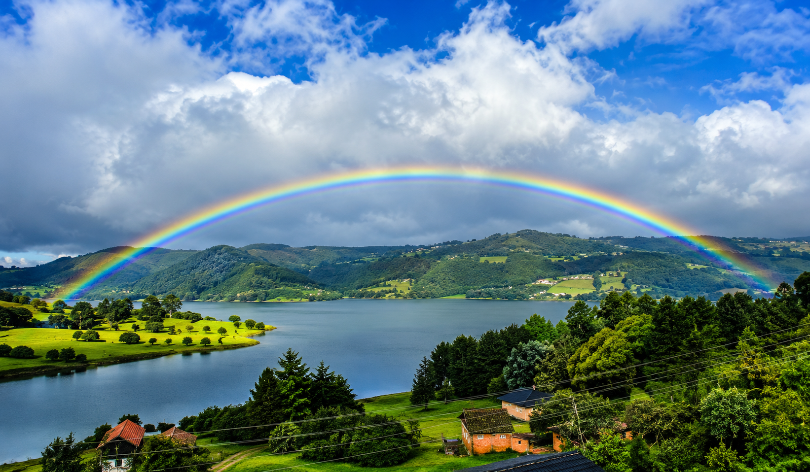 Panoramic rainbow stretching over a lake and green hills, captured during a scenic 2 day tour Zipaquira Villa de Leyva