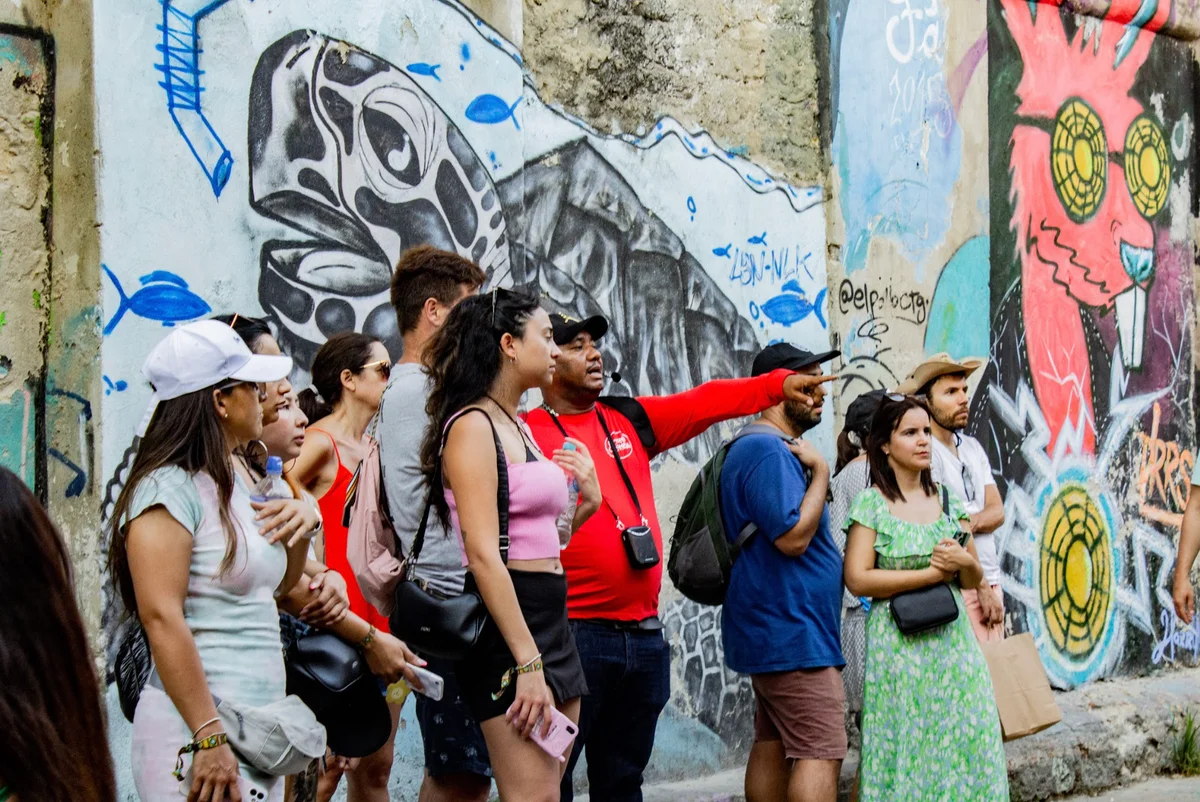 Guide showing murals to visitors during a Graffiti Tour in Cartagena, Colombia