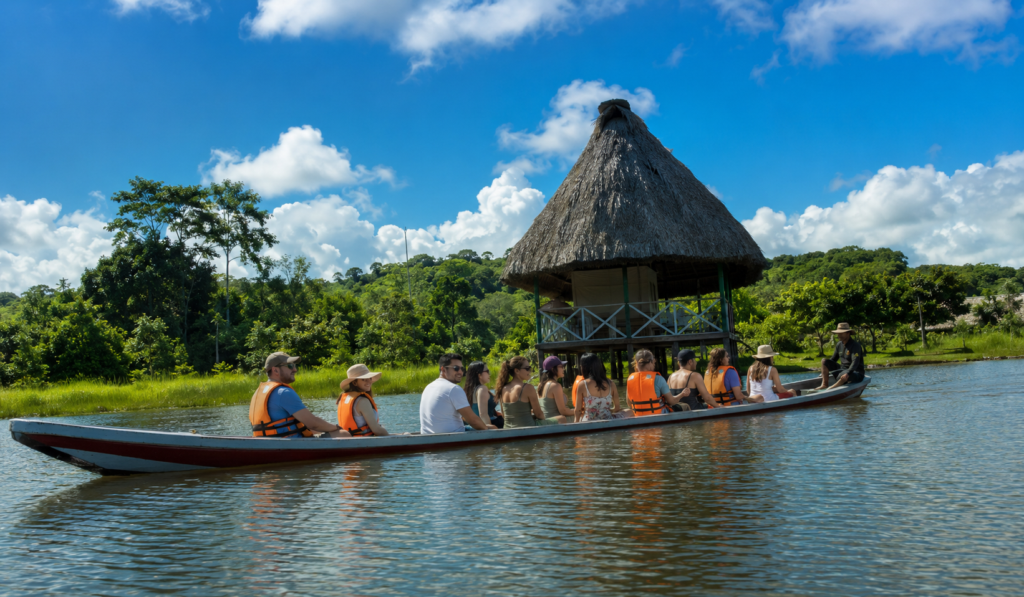 Group traveling by boat past a traditional riverside hut on a 4 day Amazon tour.