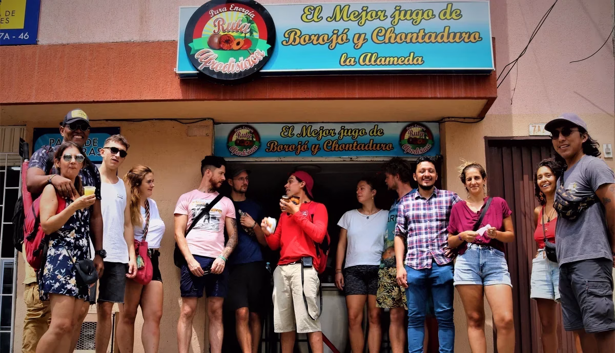 Travelers stopping for traditional borojó and chontaduro juice at a local market stand during a Food Tour Cali.