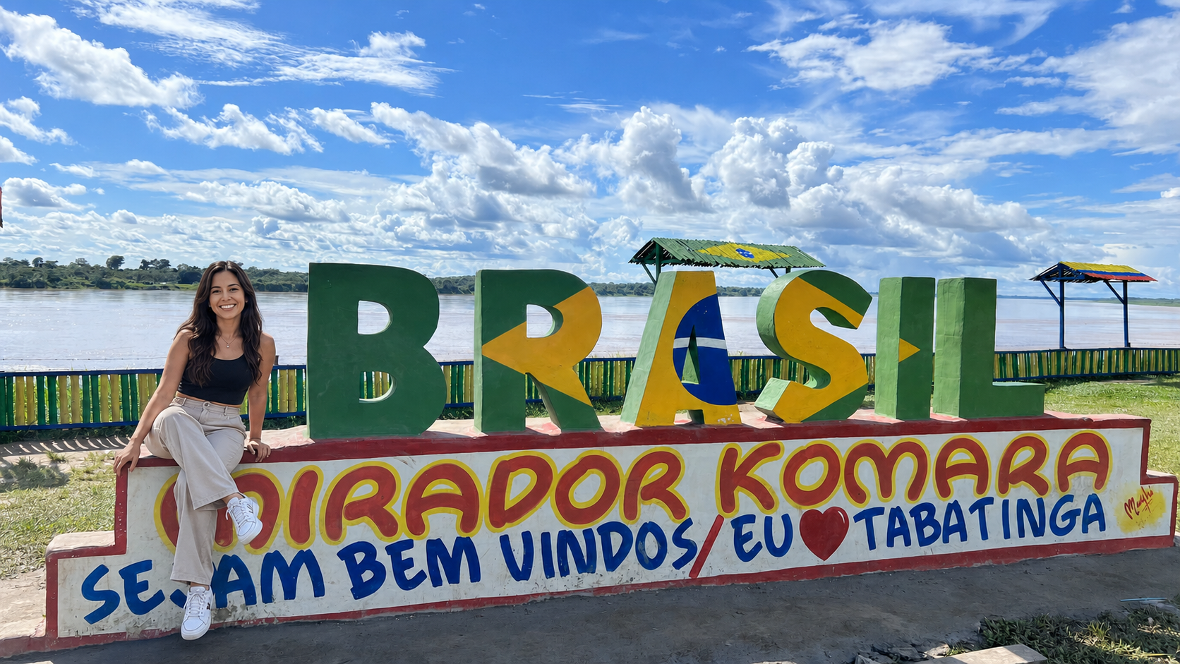 Traveler posing by the colorful Brasil riverfront sign during a City tour Leticia Tabatinga.