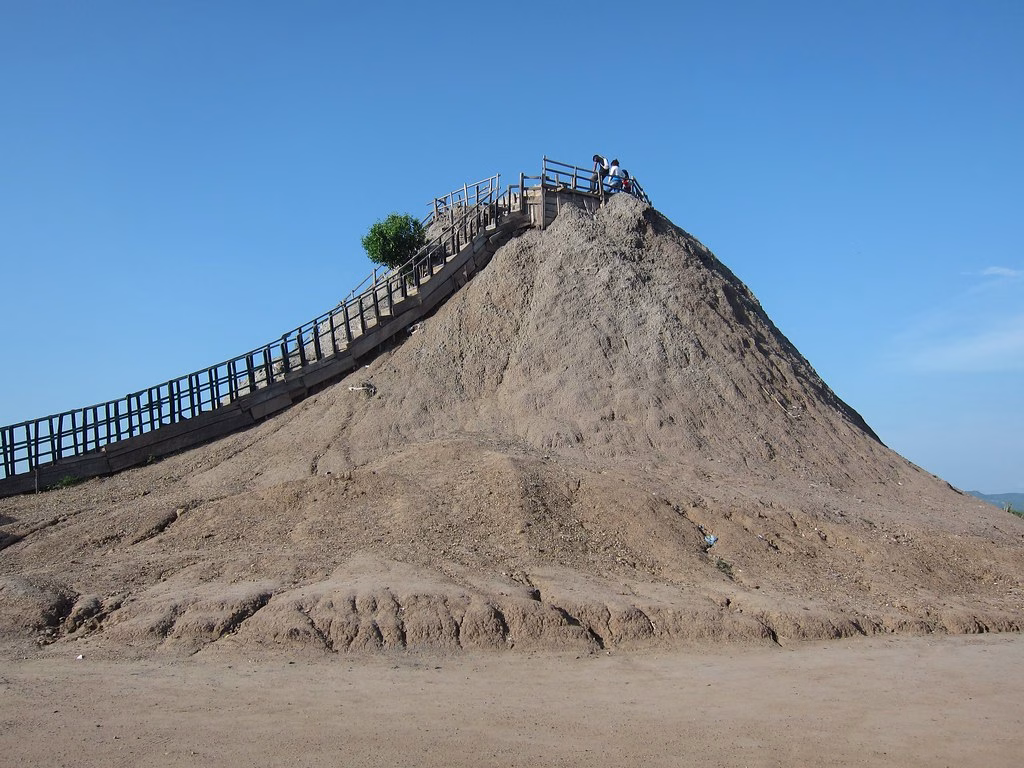 The El Totumo mud volcano from below, a cone of grey clay with a wooden staircase up its side
