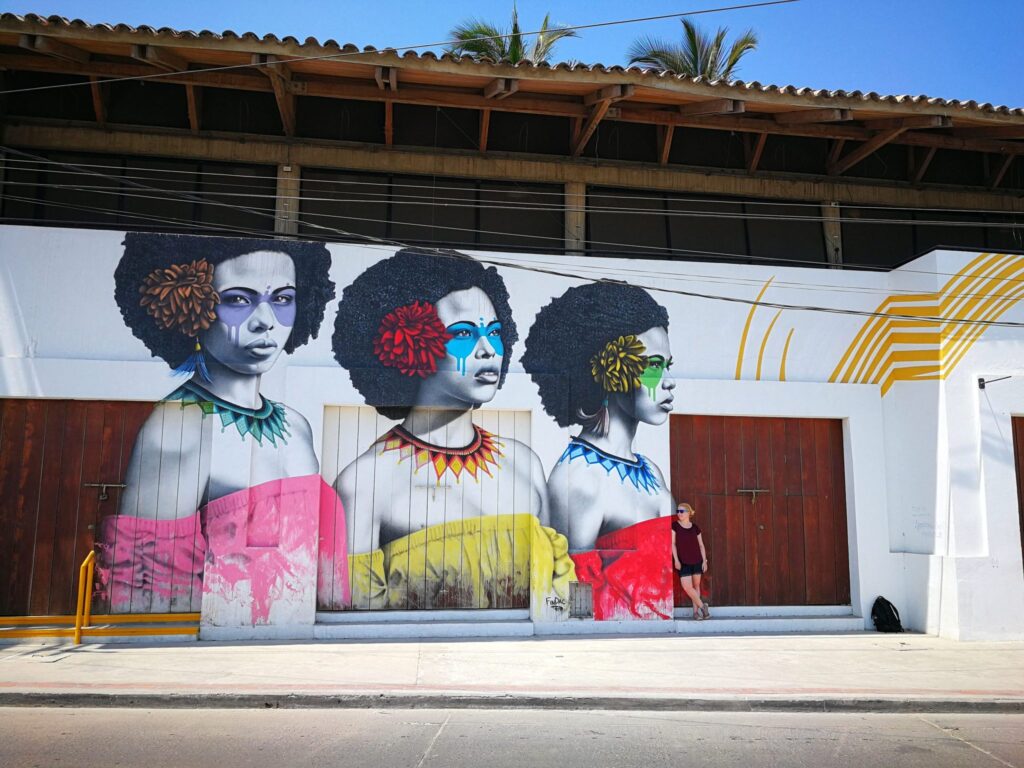 Traveler standing beside a mural of three women during a Graffiti Tour in Getsemaní, Cartagena, Colombia