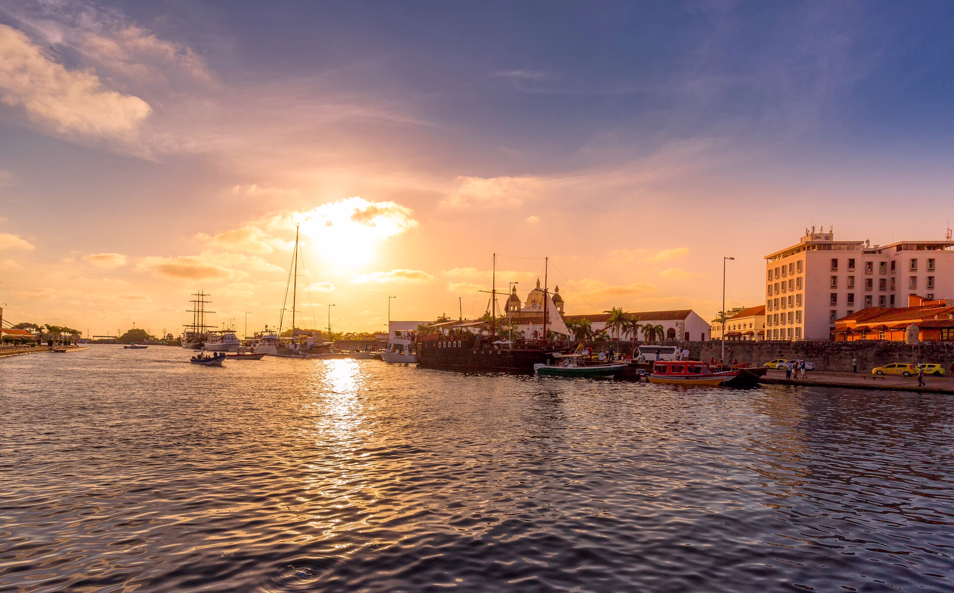 Golden sunset over Cartagena Bay with boats and skyline views during a cartagena sunset boat tour private.