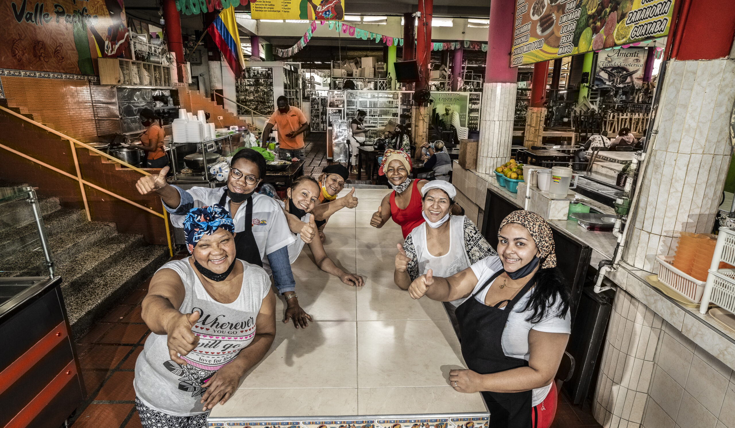 Friendly food vendors posing inside a colorful market hall featured on a Food Tour Cali.