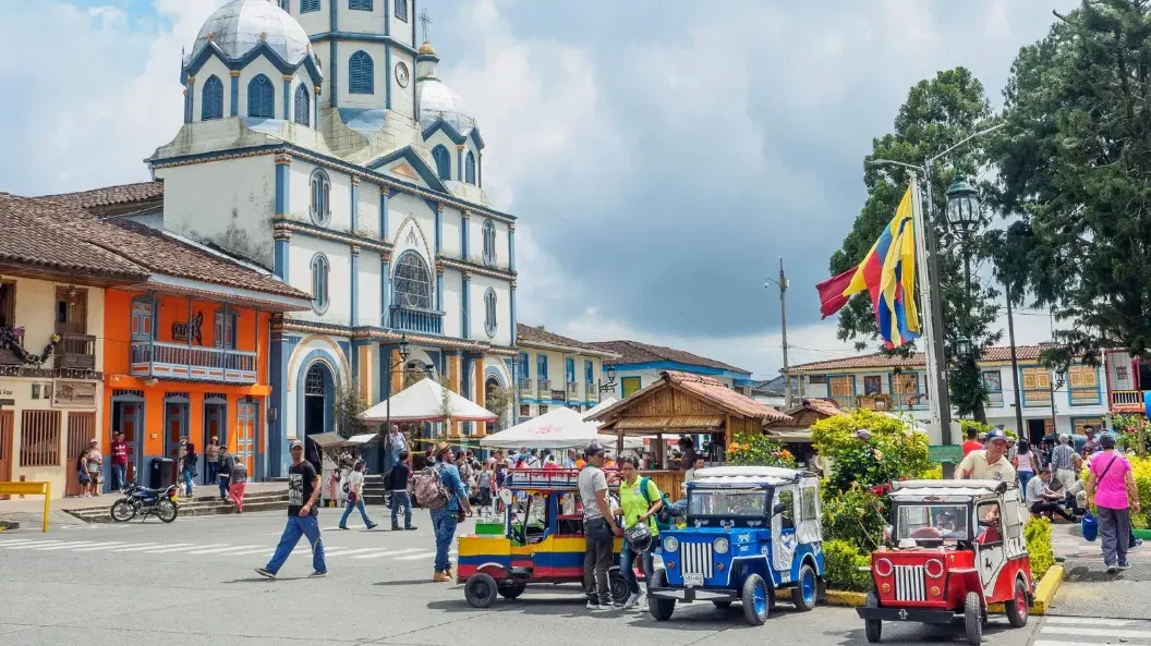 Main square of Filandia with its iconic church, colorful jeeps, and local life during a Coffee Town Tour