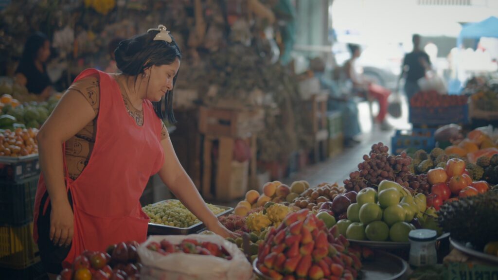 A vendor arranging fresh fruit at a stall in Cali's Alameda market