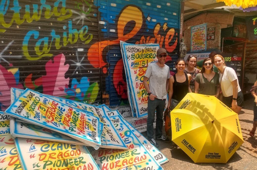 Travelers posing by a mural and street posters during a Graffiti Tour in Cartagena, Colombia