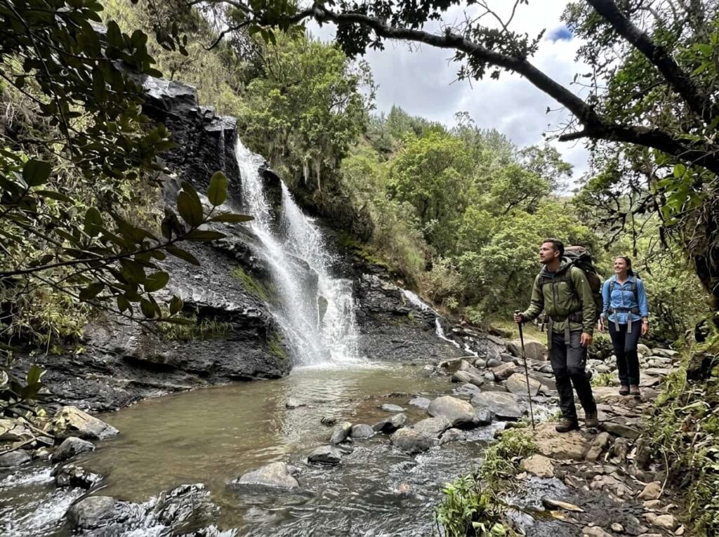 Two hikers beside the La Periquera waterfall in forest near Villa de Leyva