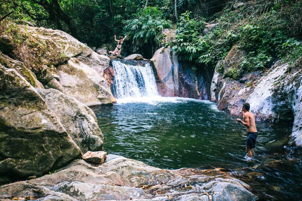 Visitors exploring and swimming near a rocky waterfall pool during a Minca Tour Santa Marta.