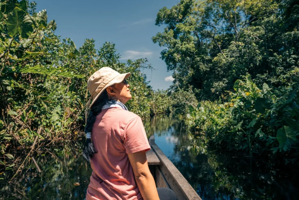 Traveler enjoying a peaceful canoe ride through narrow jungle waterways on a 5 day Amazon tour.