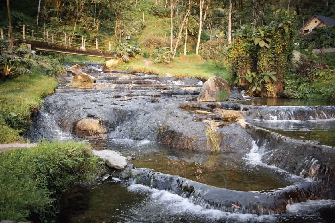 Stone thermal cascades and footbridge in the natural setting of Santa Rosa de Cabal hot springs.