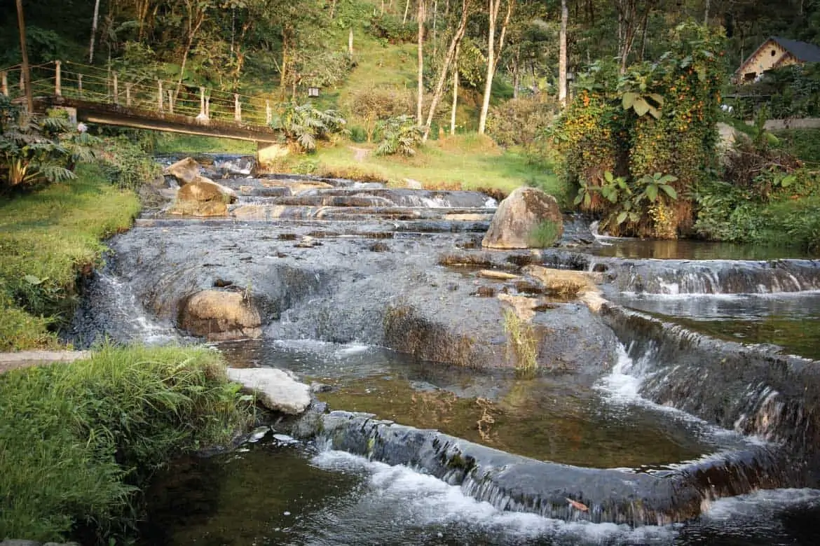 Stone thermal cascades and footbridge in the natural setting of Santa Rosa de Cabal hot springs.
