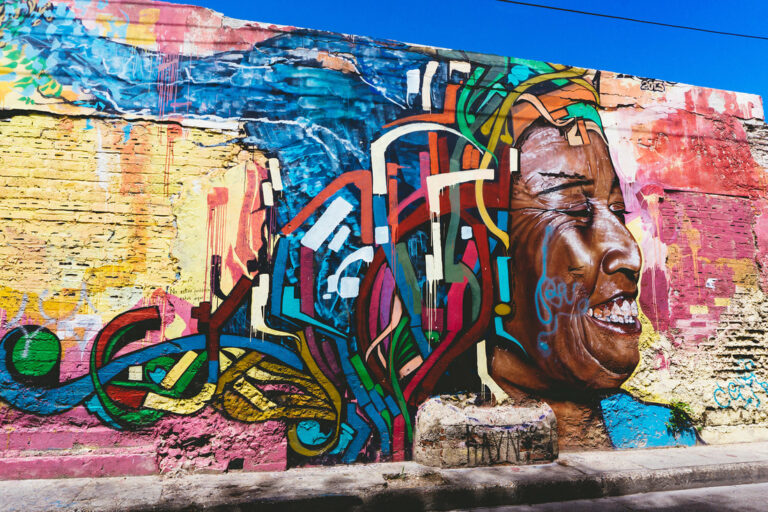 Mural of a smiling man with flying hair on a street wall in Getsemaní, Cartagena