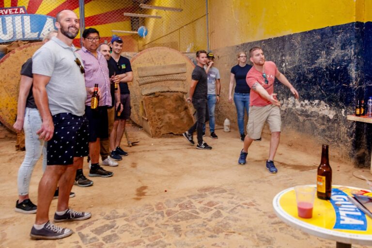 Players throwing at a tejo court with beers during a Medellín tejo night